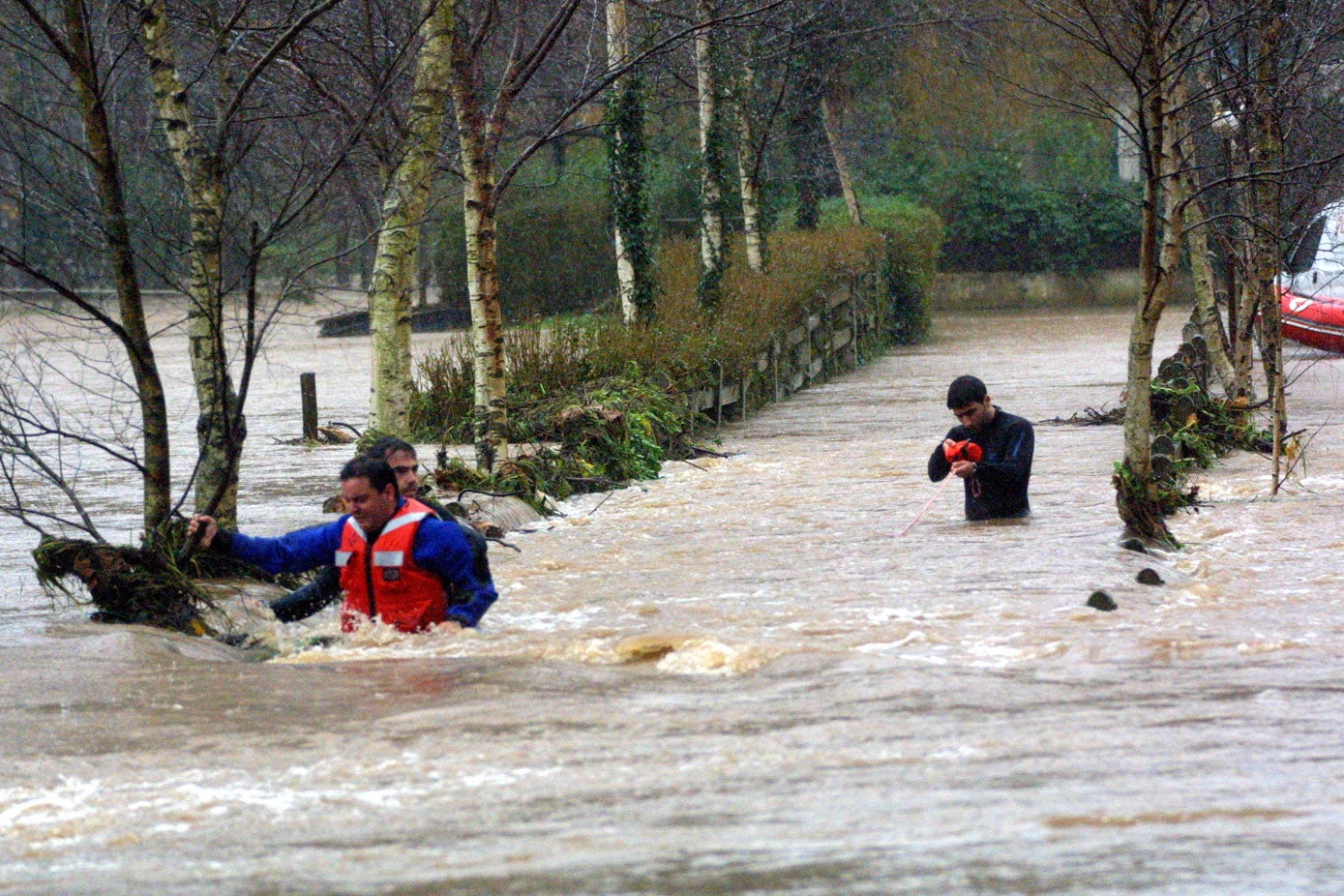 Los equipos de rescate, con el agua por encima de la cintura, en una inundación de 2002 en la zona de Piélagos.