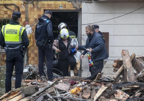 Agentes de la Policía y bomberos acompañan a vecinos a recoger enseres personales entre los escombros del edificio.