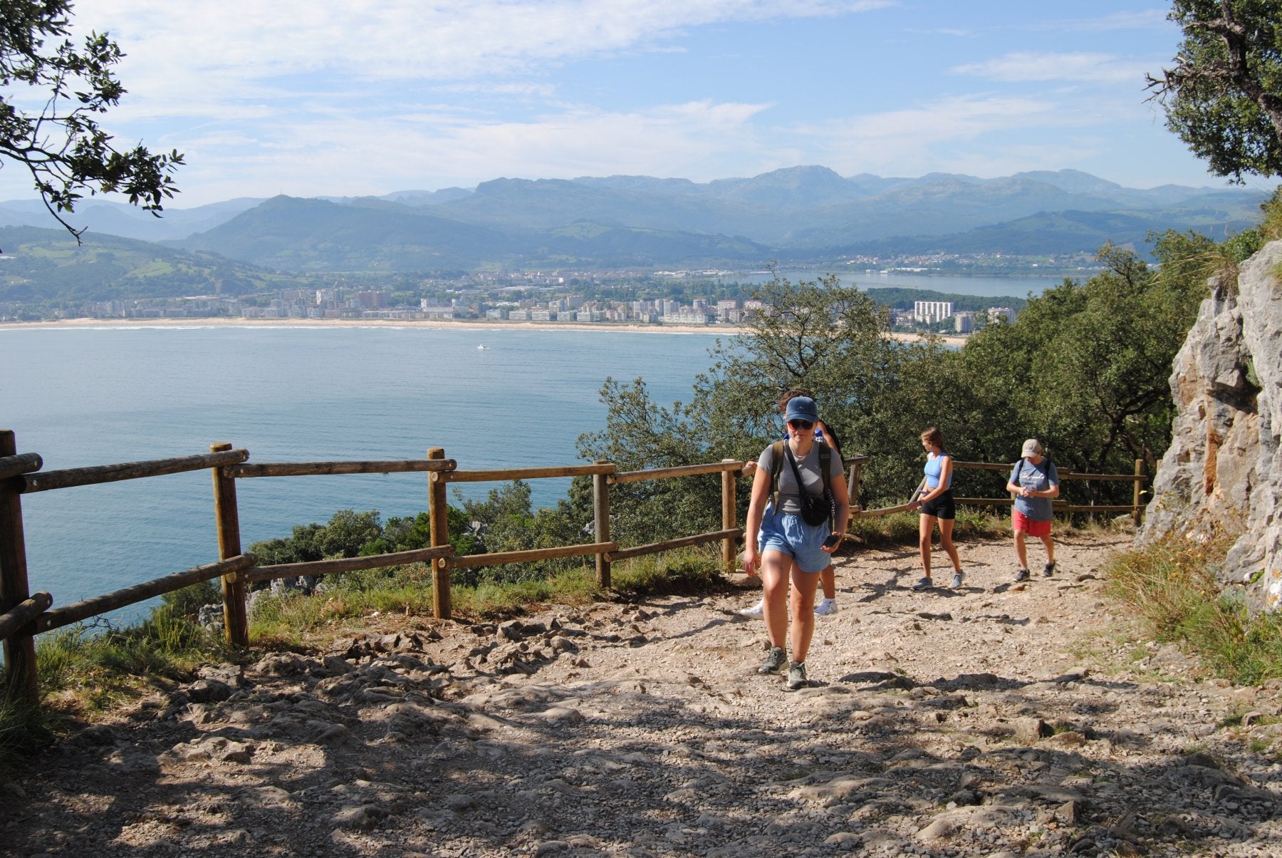 Varios senderistas, en el monte, junto al vallado de madera roto a la altura del mirador de la peña del Fraile.