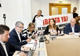 El concejal de Hacienda, Pedro Pérez Noriega, toma la palabra durante el Pleno de este martes, frente a dos vecinos que portaban una pancarta contra la subida fiscal en Torrelavega.