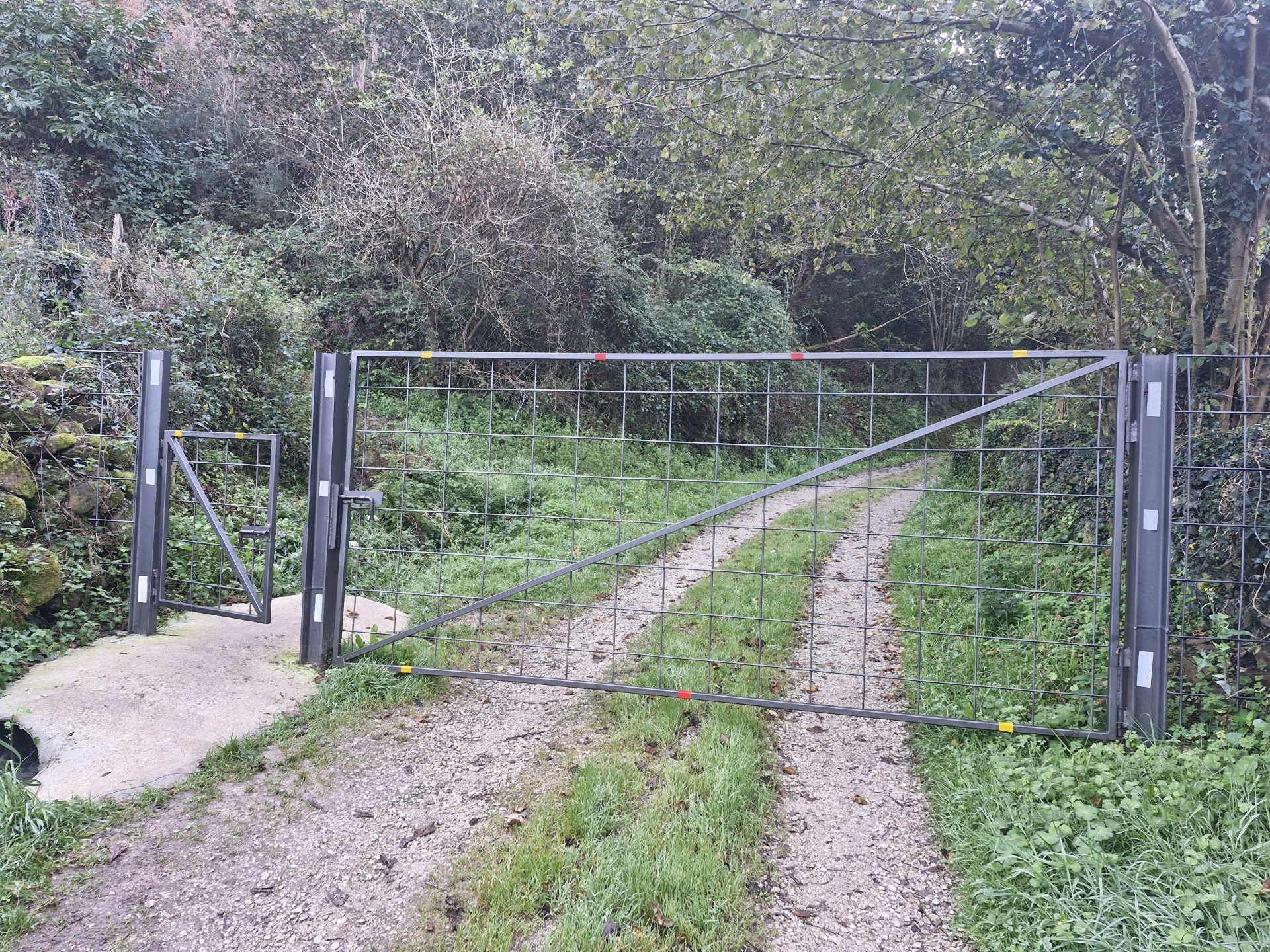 Un paso, con una portilla recientemente instalada, adentra en el monte.