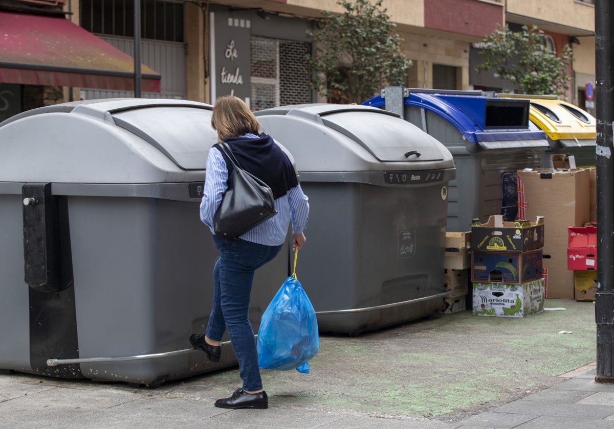 Una vecina se dispone a tirar la basura en un contenedor en Camargo.