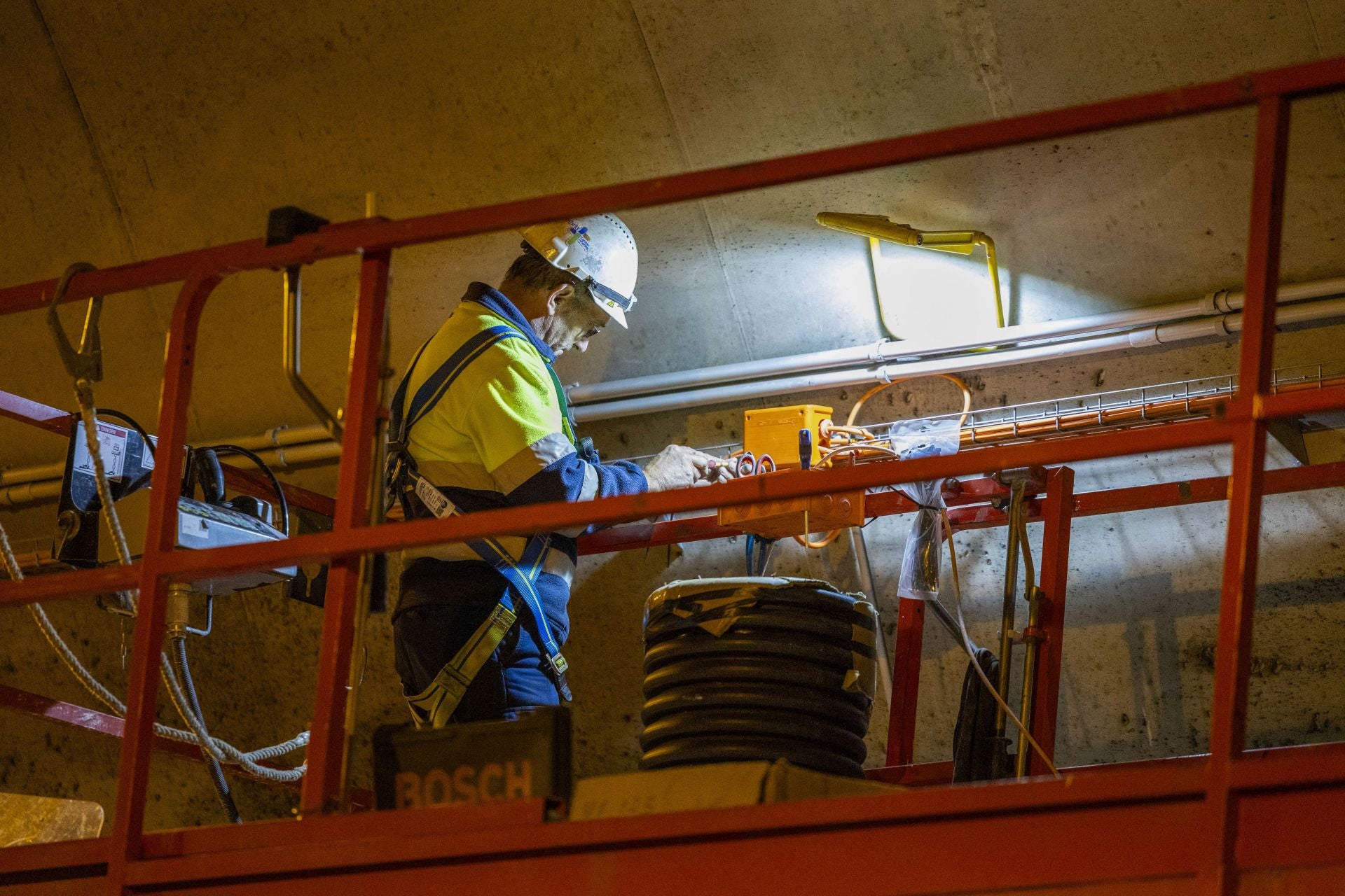 Un obrero, sobre un elevador, ajusta la instalación.