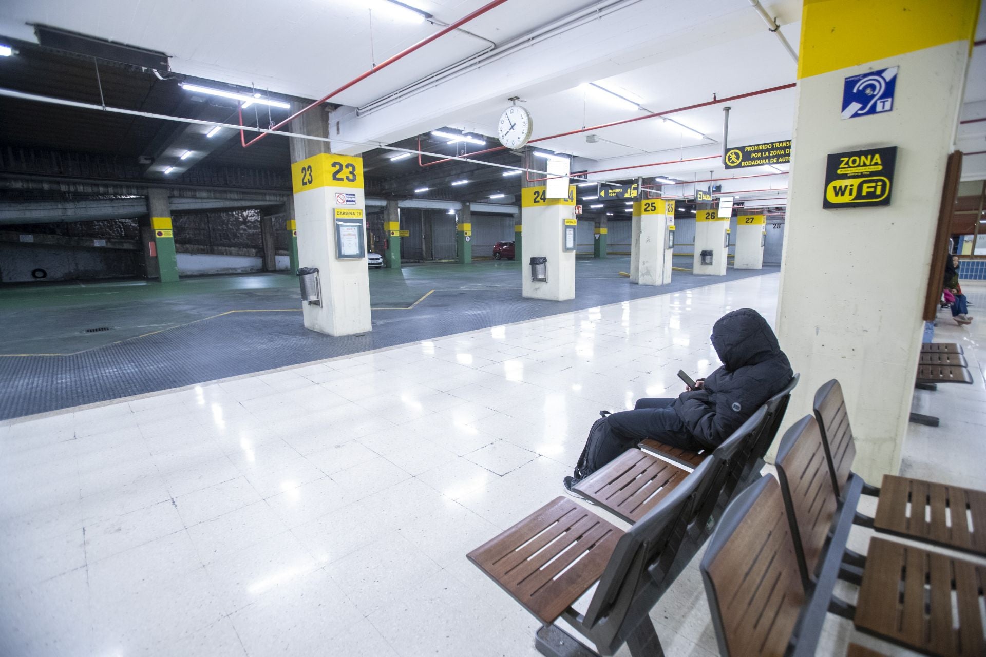 Un viajero espera a primera hora la llegada de los primeros autobuses en Santander. 