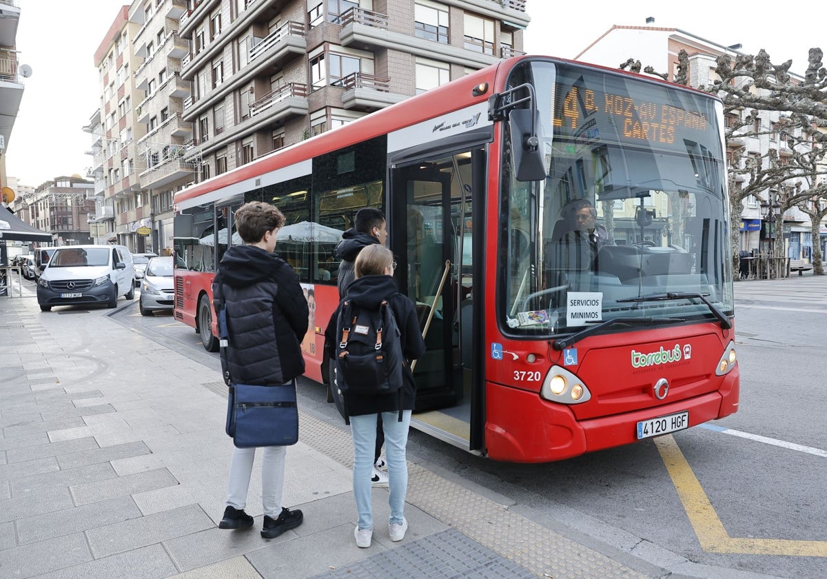 Jóvenes suben a un Torrebús, este jueves, en la calle Augusto González Linares de Torrelavega.