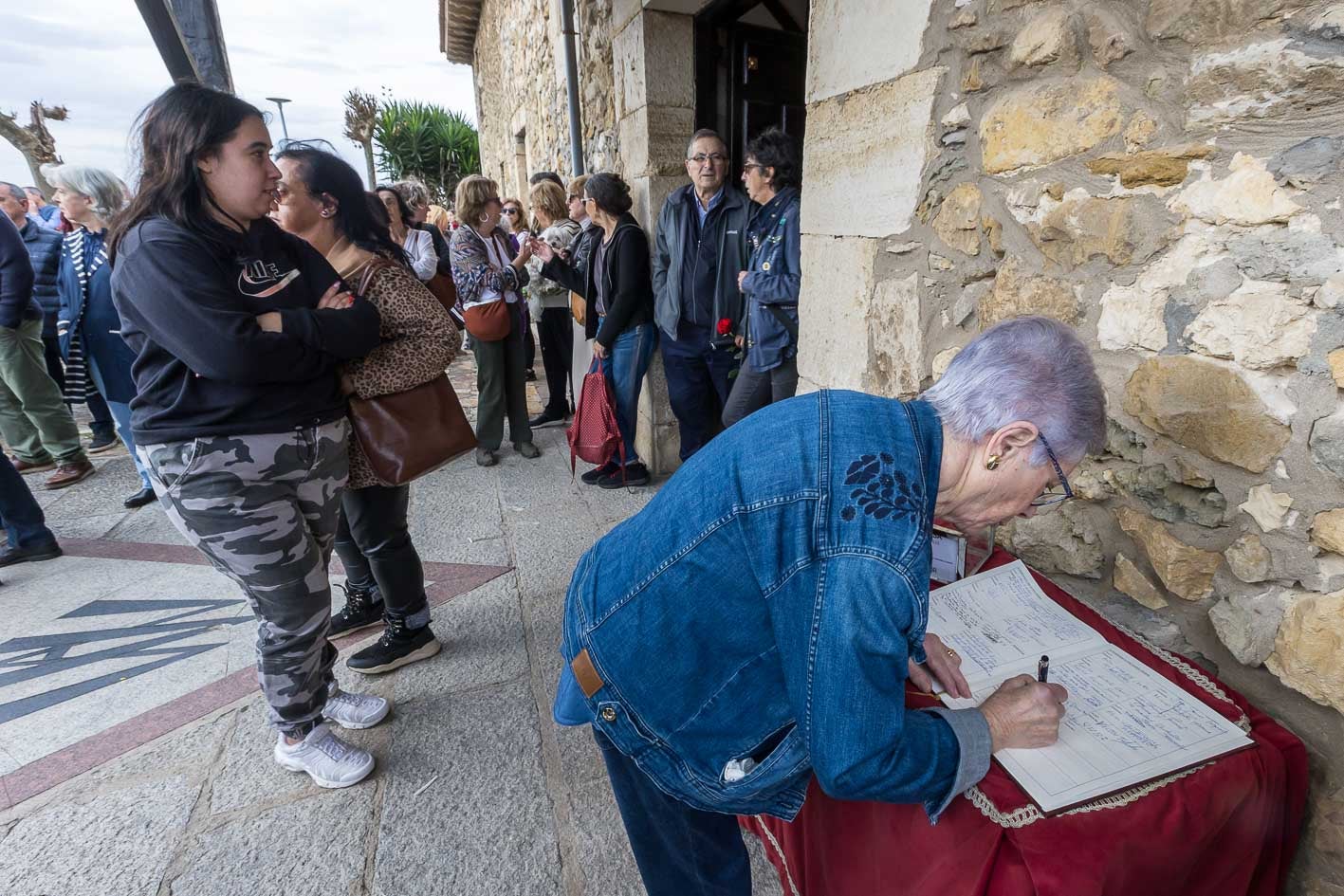 Una asistente firma el libro de condolencias.