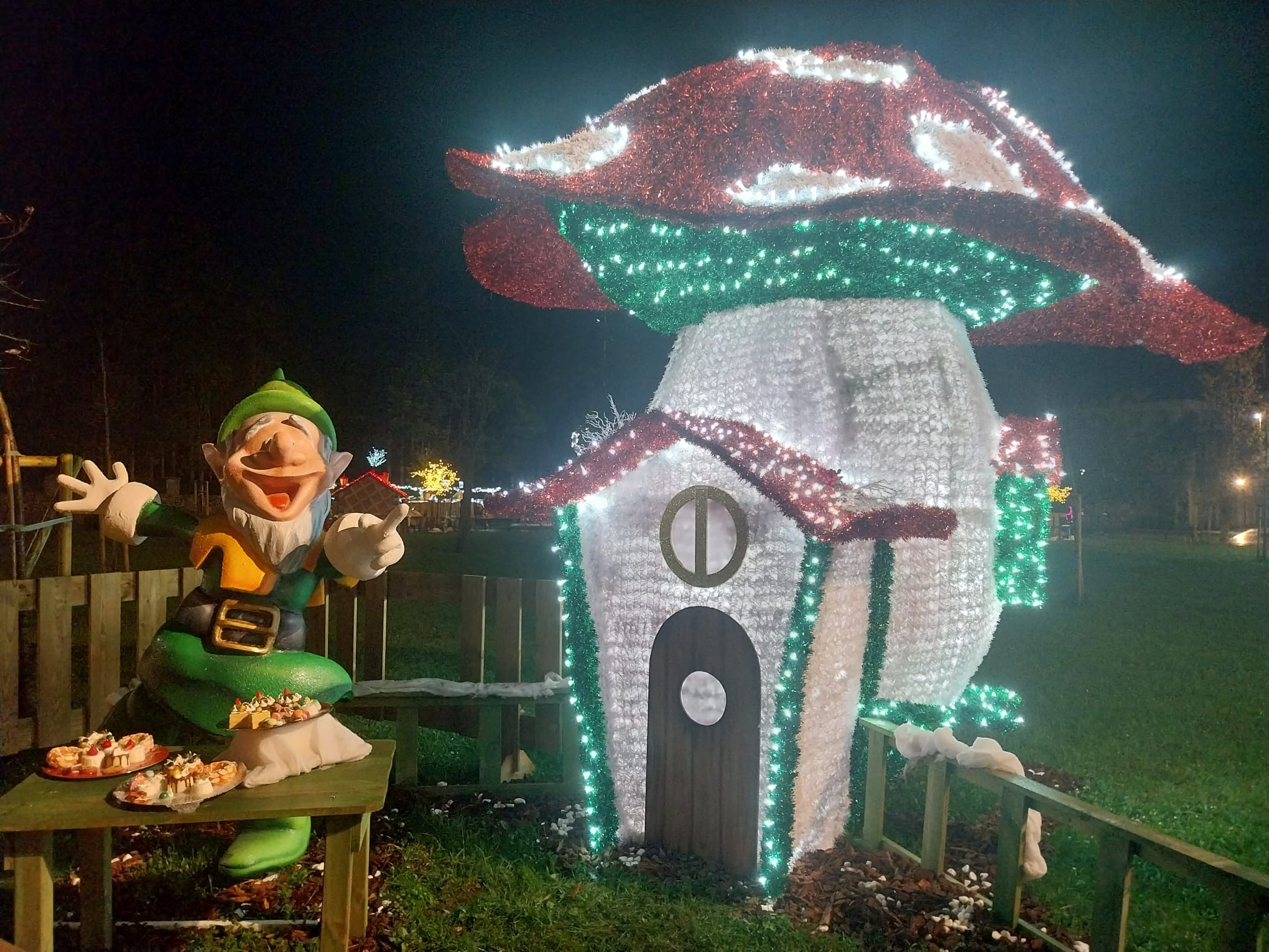 Un elfo junto a su iluminada casa en forma de seta. 