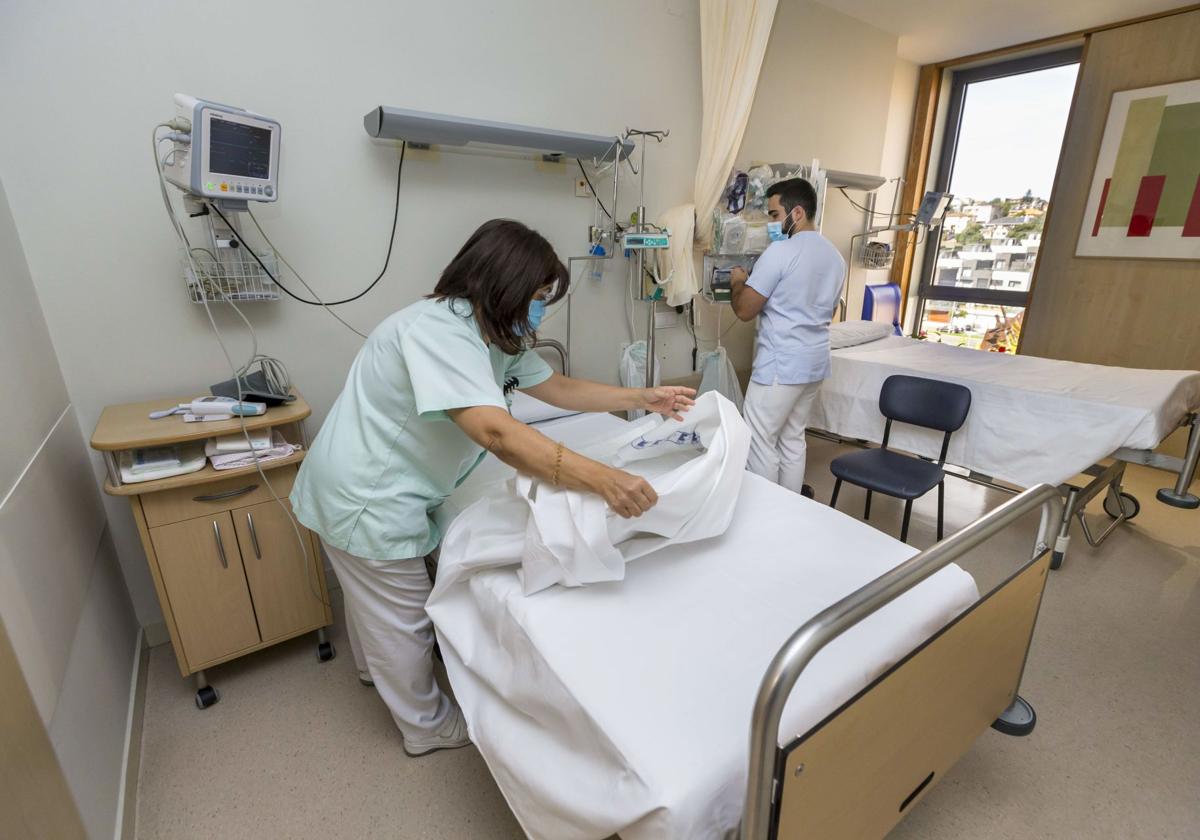 Personal sanitario prepara una de las habitaciones dobles del Hospital Valdecilla para el ingreso de los siguientes pacientes.