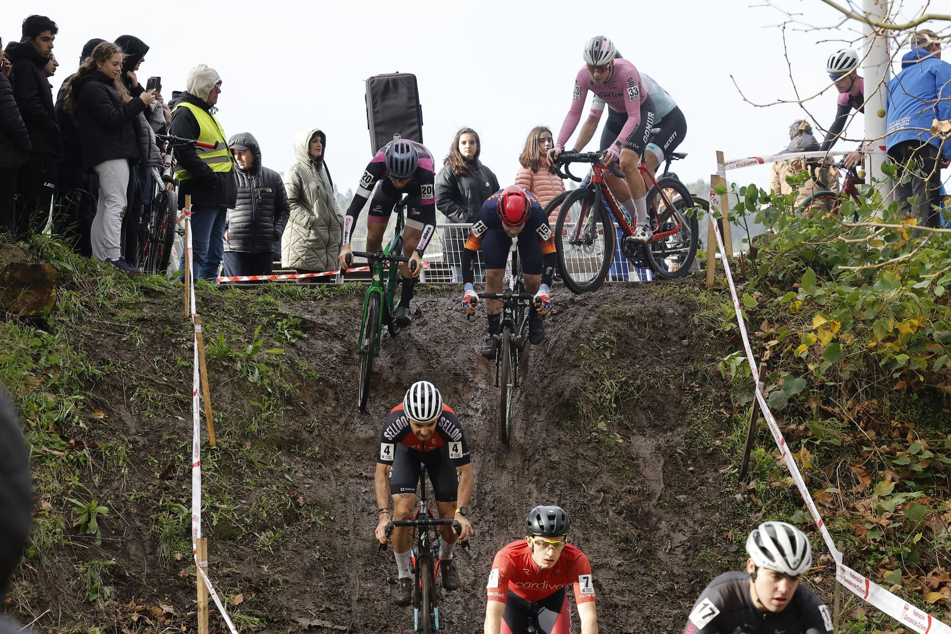 Varios ciclistas, en un tramo de bajada cerca de la zona de la salida y meta.