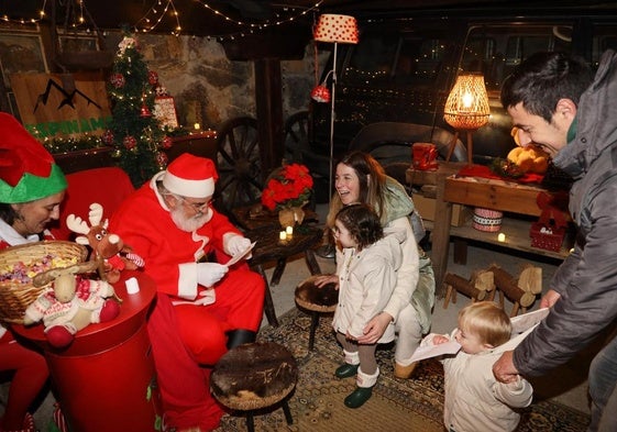 Dos niños acompañados por sus padres entregan su carta a Papá Noel en Espinama