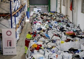 Un operario del servicio recoloca productos en una bolsa en el depósito de Barreda, que almacena unas 16 toneladas de ropa desde julio.