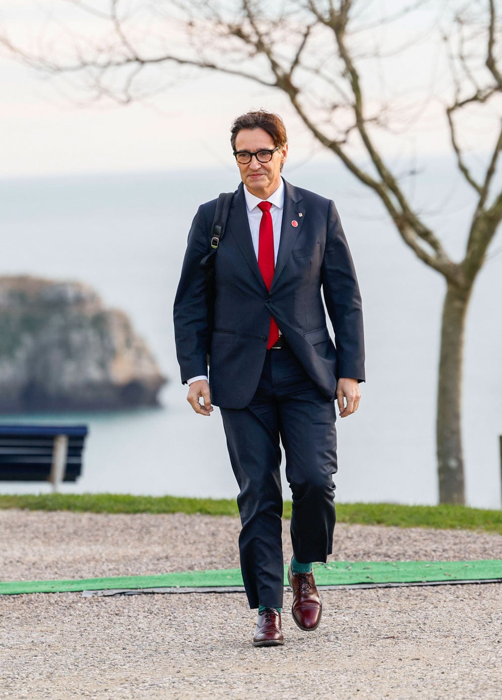 Salvador Illa, presidente de Cataluña, con traje azul, corbata roja y calcetines verdes. 