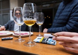 Un grupo de personas toma unas cañas y fuma en una terraza.