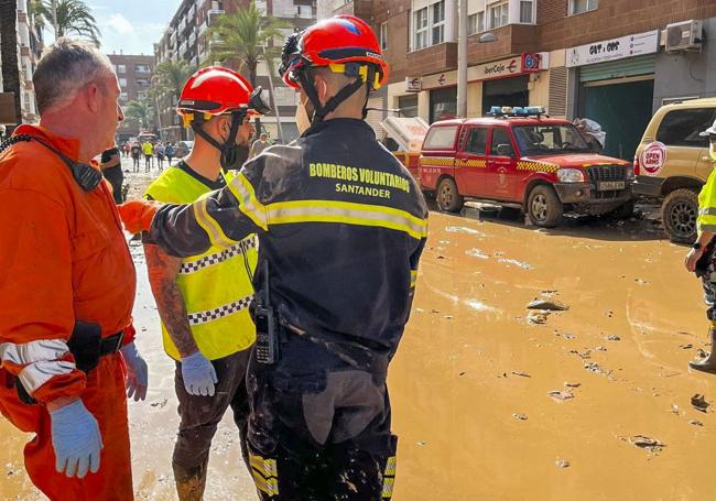 César Parás, bombero voluntario de Santander, en Paiporta junto a un Policía Local y un miembro de Protección Civil.