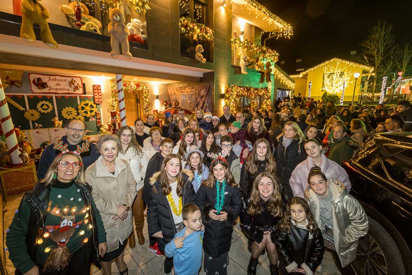 Las familias que han tematizado de Navidad sus hogares en Quijano posa delante de una multitud de visitantes.