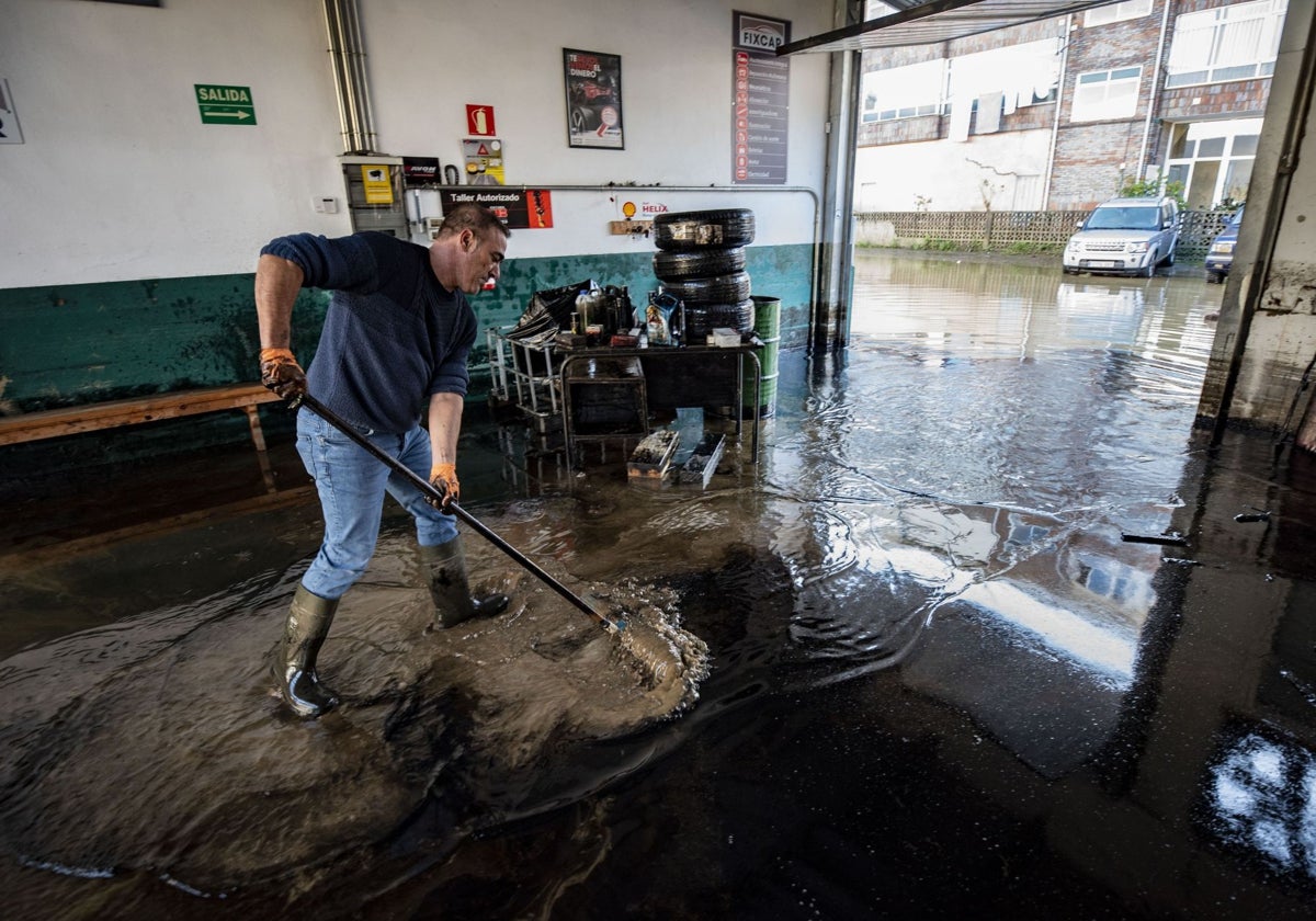 Un hombre limpiando en su negocio tras las inundaciones de 2021 en las calles de Ampuero.