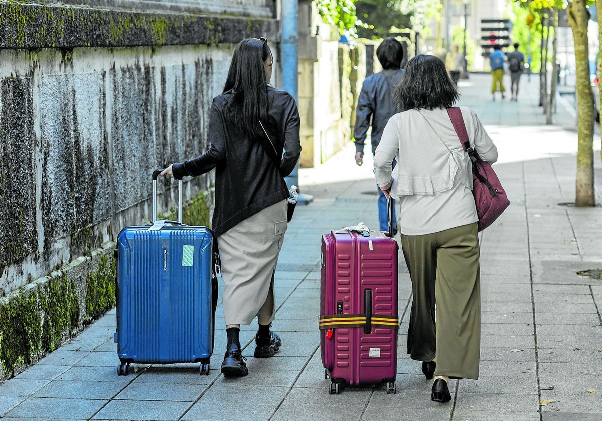 Dos turistas transportan sus maletas por las calles de Santander.