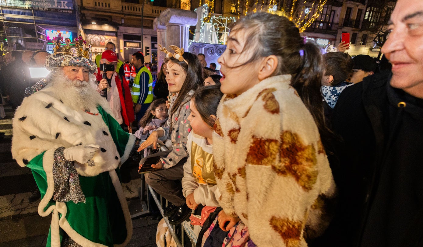 Melchor saluda a los niños a su llegada a la plaza del Ayuntamiento, antes de entregar sus regalos al Niño Jesús y subir al balcón para dedicar unas palabras a las miles de personas que los esperaban.