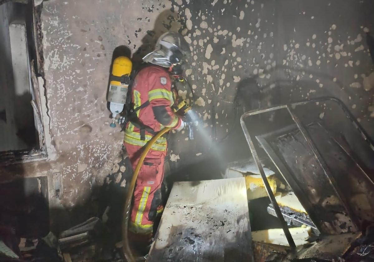 Un bombero actúa sofocando el fuego de la vivienda afectada.