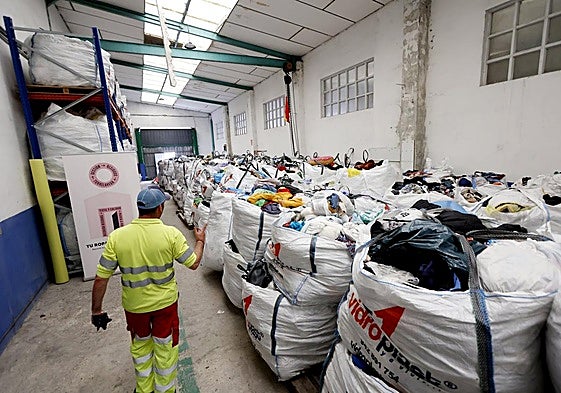 Un operario de Recogida de Residuos trabaja en el almacén del servicio, abarrotado de ropa.