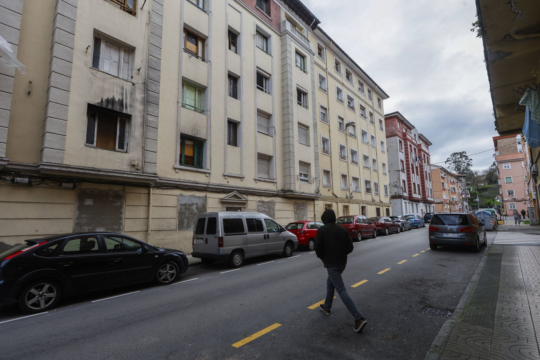 Un vecino cruza la calle junto al número 9 de la calle Marqueses de Valdecilla y Pelayo, ayer, en La Inmobiliaria (Torrelavega).