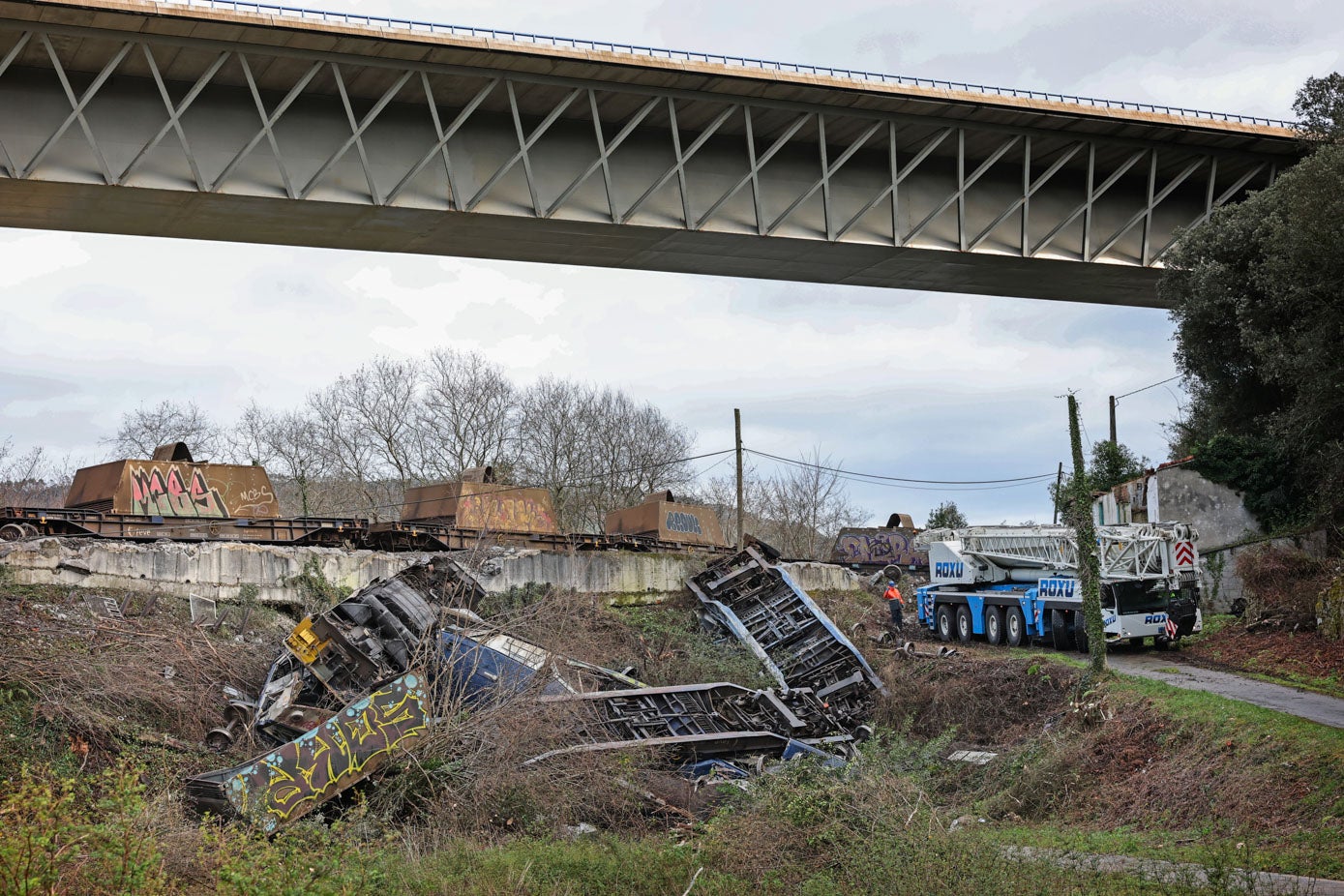 Una grúa de gran tonelaje procedente de Asturias ha llegado a media mañana de este martes a la zona para retirar los vagones y la carga desperdigada por los taludes.