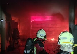 Bomberos sofocando el fuego del garaje.