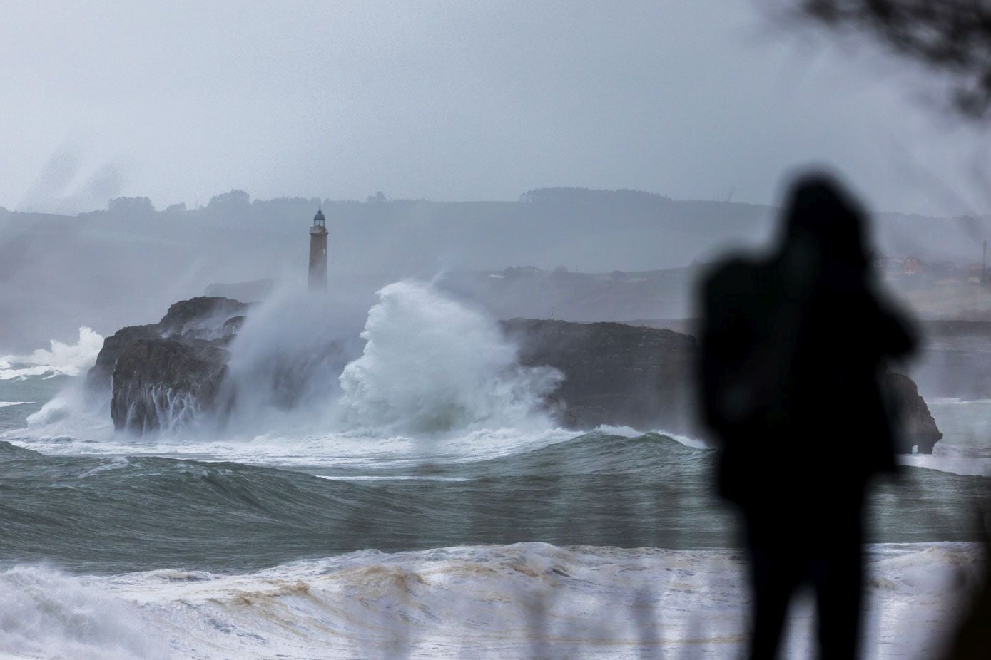 Un vecino de Santander observa el temporal marítimo que golpea la isla de Mouro.