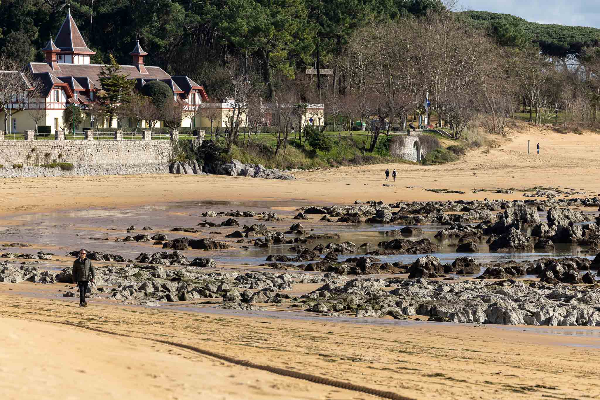 Estado actual de la playa de Los Bikinis, con varias personas disfrutando de un paseo tras las labores de mantenimiento en el arenal.