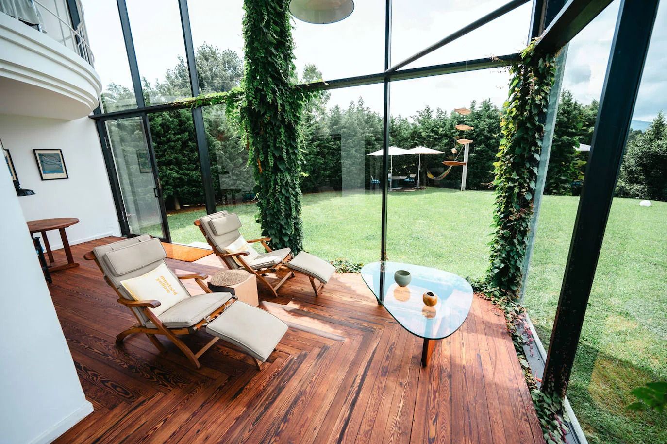 Un rincón donde la naturaleza abraza el hogar. La madera del suelo aporta calidez, mientras el ventanal conecta el interior con el jardín en esta casa de la ría de Cubas.