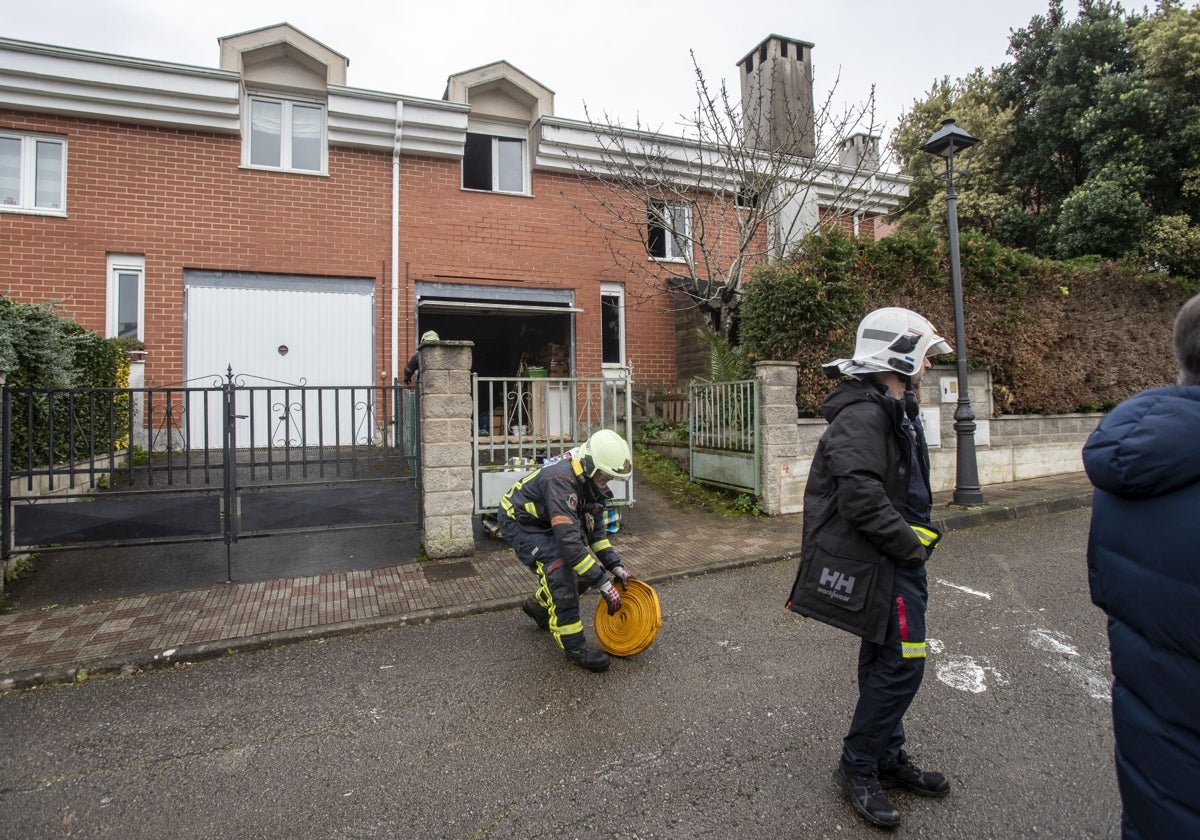 Dos bomberos recogen el material empleado para sofocar el incendio.