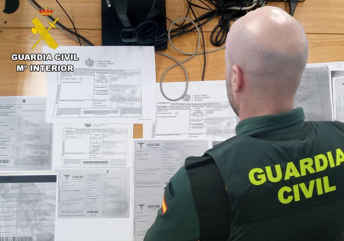 Un agente de la Guardia Civil examina los documentos falsificados.