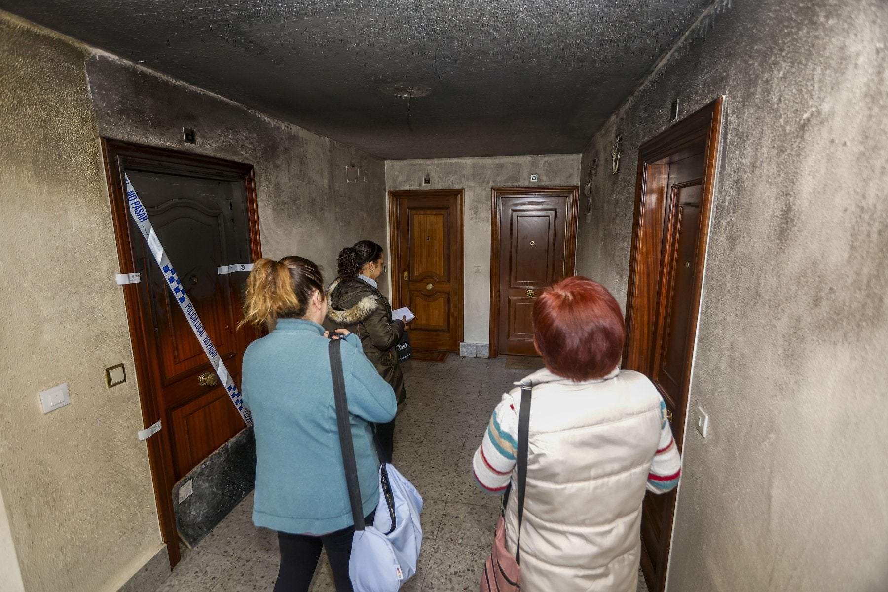 Alicia, María Luisa y Paula charlan en el rellano de su escalera, junto a la vivienda precintada donde se desató el incendio.