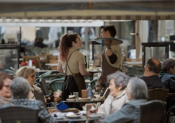 Una camarera junto a un compañero atienden una terraza.