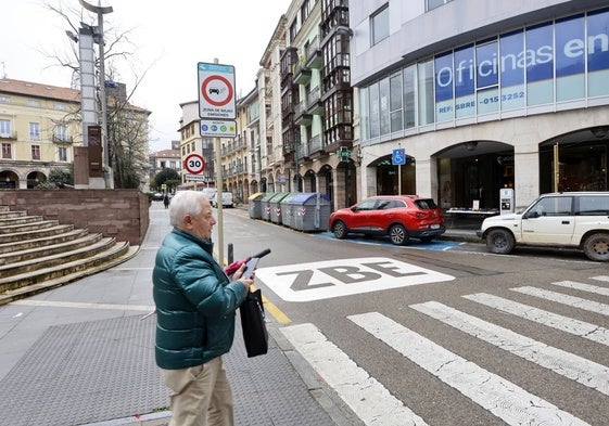 Un vecino camina por el centro de Torrelavega, junto a una señal horizontal de la Zona de Bajas Emisiones ubicada en la calle Francisco Díaz, junto a la Plaza Mayor.