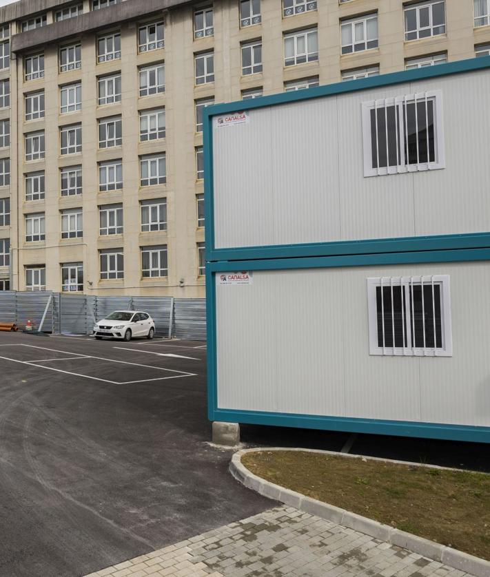 Imagen secundaria 2 - A la izquierda, entrada a la zona de la obra del búnker de Valdecilla, que ya está vallada. A la derecha, casetas de obra en el aparcamiento de la Facultad de Enfermería.