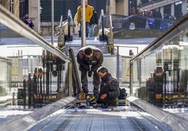 Dos trabajadores de TK Elevadores reparan un tramo de escaleras mecánicas en Santander