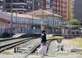 Una vecina cruza el paso a nivel de Pablo Garnica, con la estación ferroviaria Torrelavega-Centro al fondo.