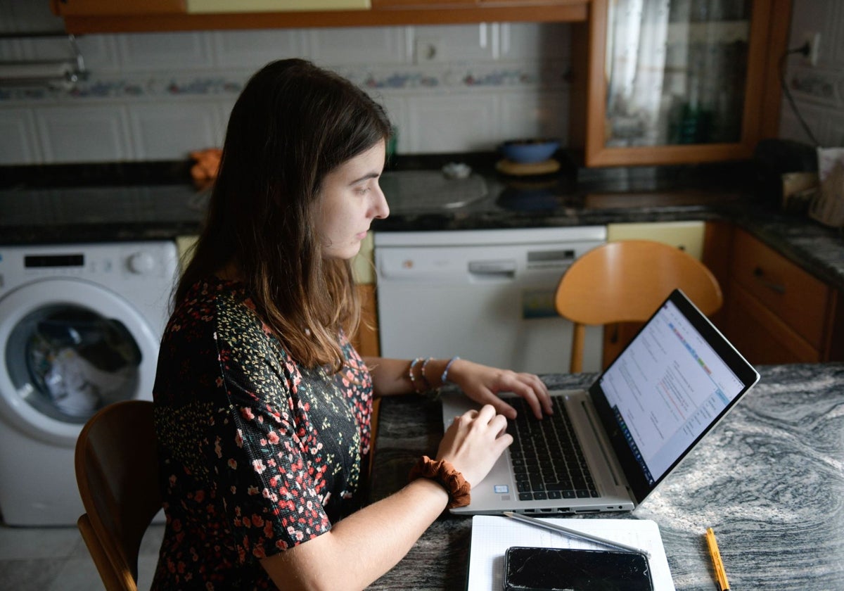 Una mujer teletrabaja con su ordenador desde su cocina.