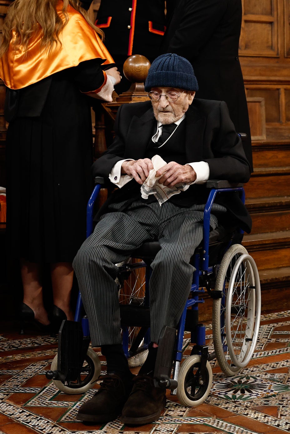 Álvaro Pombo en su silla de ruedas a la llegada al paraninfo universitario de Alcalá de Henares.