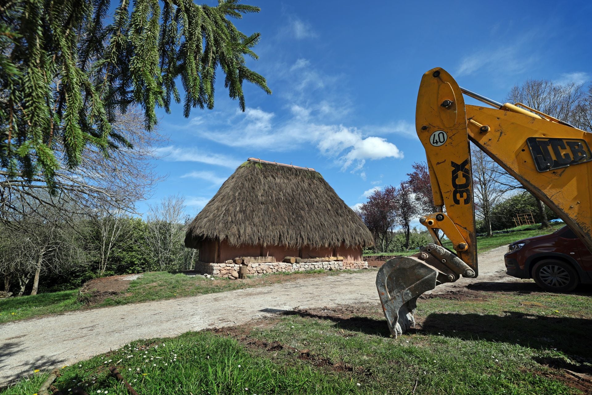 Una pala excavadora junto a la cabaña rectangular recién restaurada.