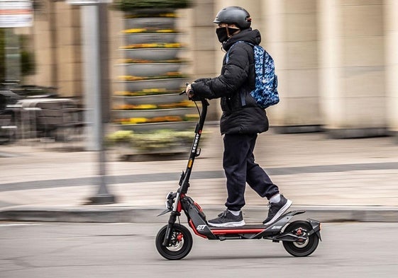 Un hombre circula en patinete eléctrico y utiliza el casco.