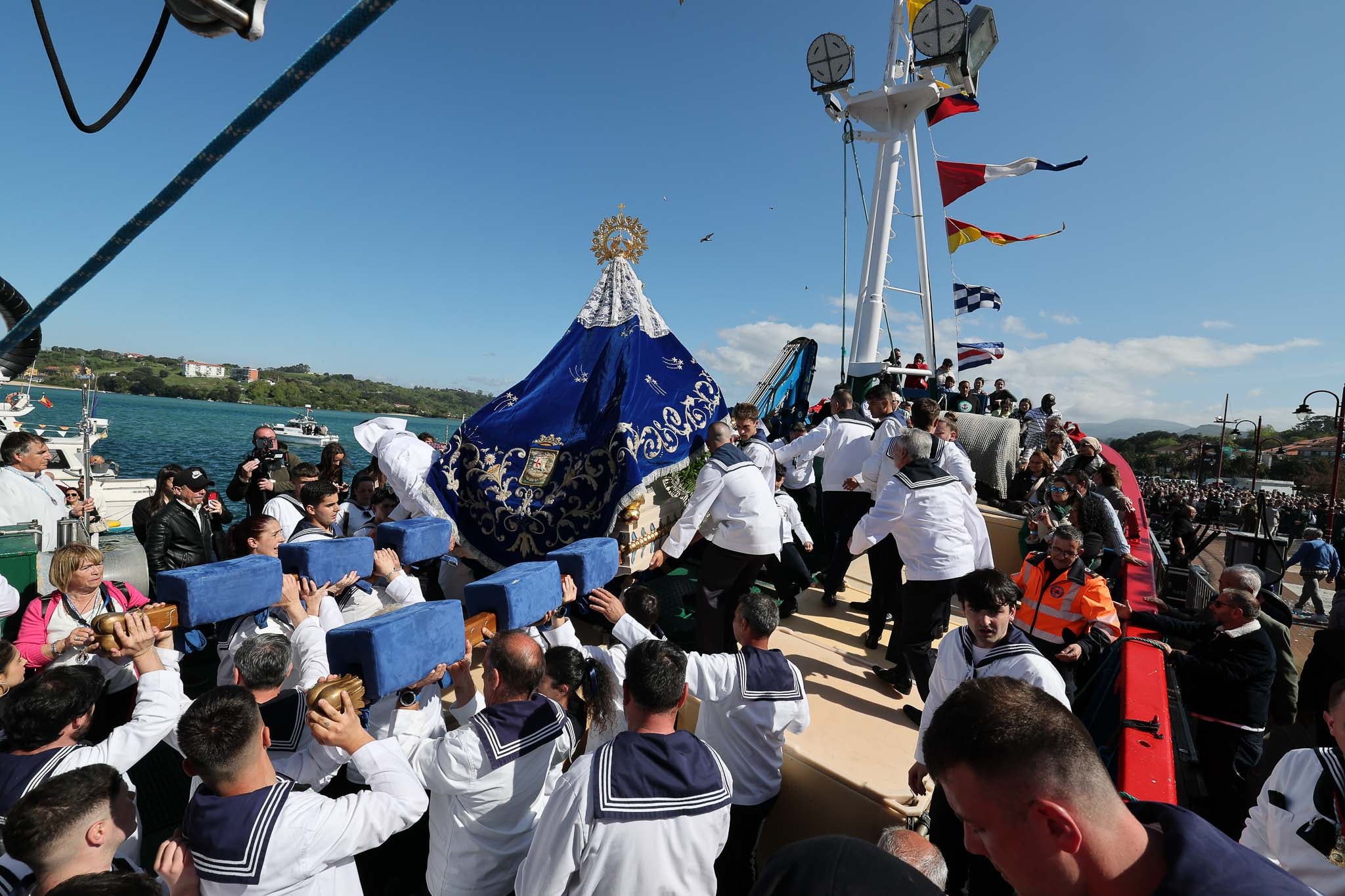 Los picayos colocando las andas de la Virgen en el pesquero para iniciar la procesión marítima