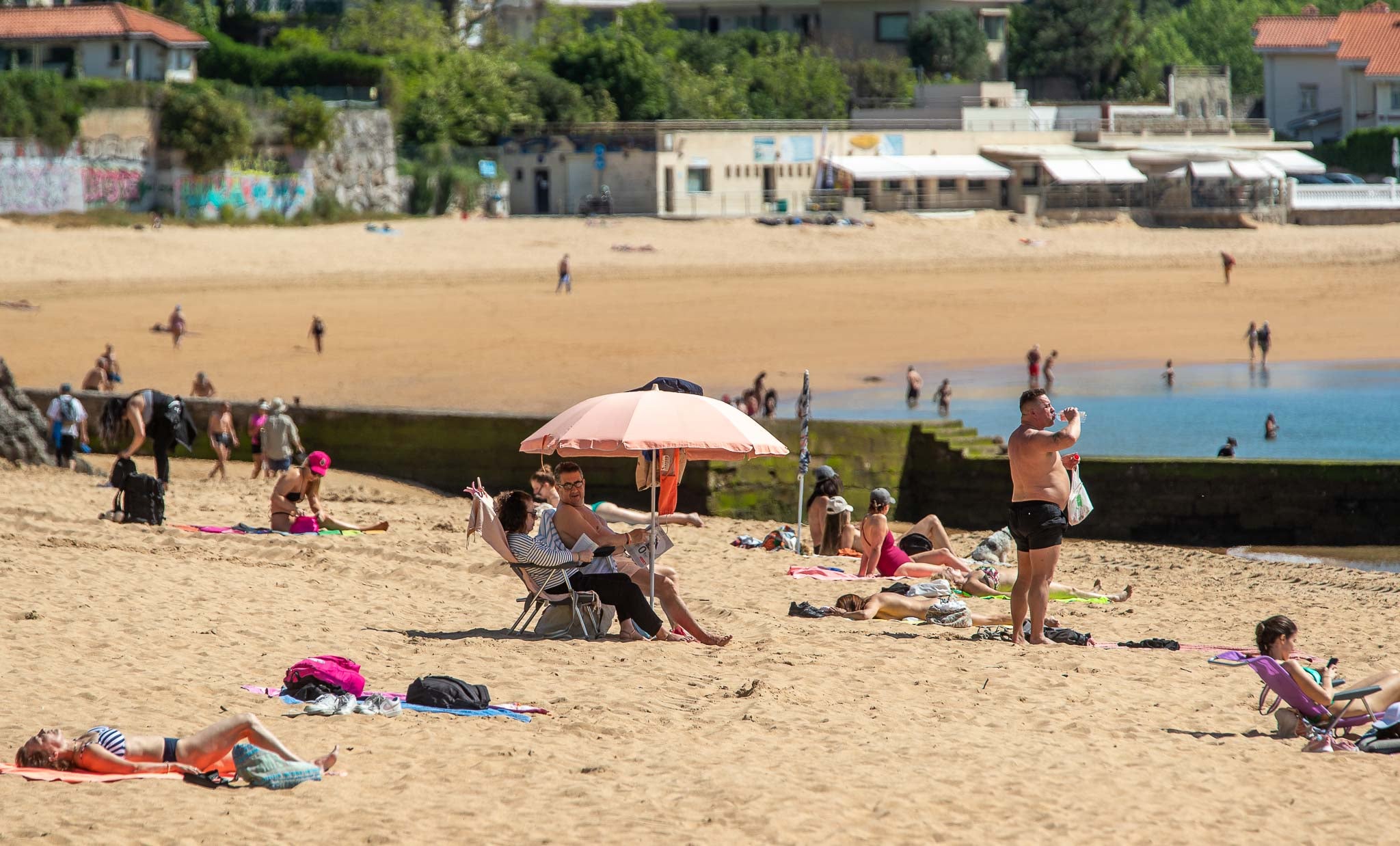 Ciudadanos tomando el sol y refrescándose en la playa de Los Peligros