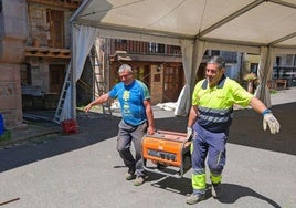 Dos operatios del Ayuntamiento de Valdáliga mueven un generador a gasolina, con el que trabajan en pueblos como San Vicente del Monte.