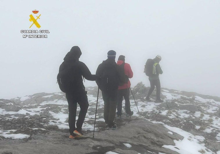 Los jóvenes guiados entre la niebla por uno de los rescatadores del Greim de la Guardia Civil.