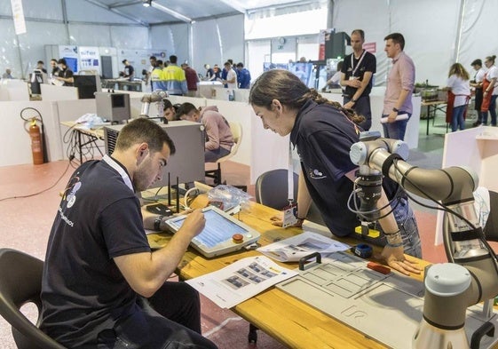 Dos alumnos de FP programan un brazo robot.