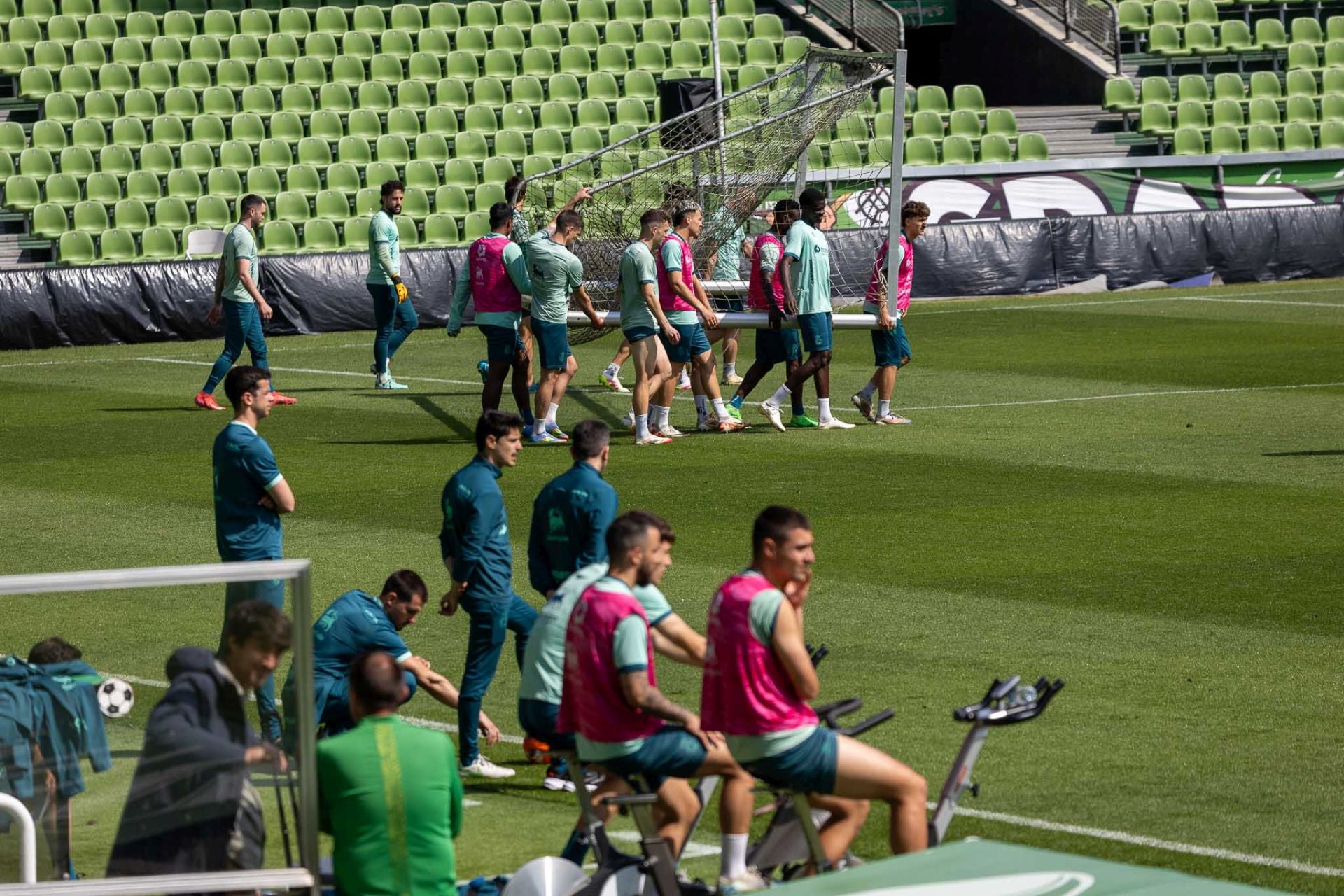 Una parte de los jugadores mueve una de las porterías, mientras que otra realiza ejercicio.