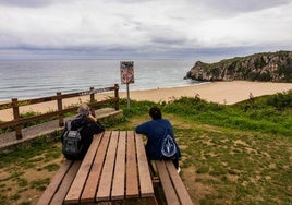 Dos personas observan la playa de Usgo desde el mirador.