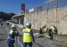 Dos trabajadores supervisan las obras de reparación del puente de Somo.